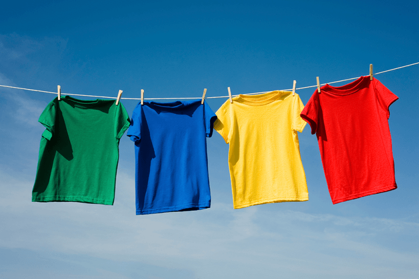 Four brightly colored tee shirts hanging on clothesline